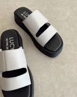 Sandalias bajas de cuero vacuno color blanco con plataforma negra y ajuste con velcro.
