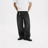 Jean de corte ultra baggy color negro, confeccionado en denim de algodón con textura rústica. Presenta un diseño de pierna ancha y tiro medio.