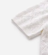 Camisa polo blanca de manga corta con cuello y tejido de punto con textura calada en forma de rombos.