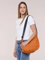 Cartera bandolera de lona naranja en forma de medialuna, con correa ajustable negra y cierre principal.
