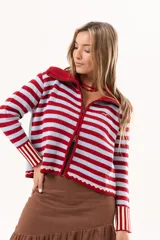Saco tejido de punto a rayas horizontales en color celeste y rojo, con cuello alto, cierre frontal doble deslizador y puños con diseño en contraste. Presenta un pequeño bordado en el pecho.