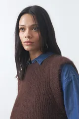 Chaleco de punto con textura afelpada, cuello redondo y hombros marcados. Presenta una silueta relajada y un diseño sin mangas.