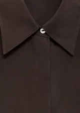 Camisa de seda de corte oversize, color marrón chocolate, con cuello camisero, mangas largas con puños abotonados y cierre frontal de botones ocultos.