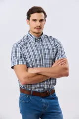 Camisa de manga corta con estampado de cuadros en tonos azules, rojos y blancos, cuello con botones y bolsillo ojal en el pecho con logo bordado.