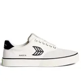Championes urbanos Cariuma modelo Naioca Pro, confeccionados en una combinación de lona y gamuza en color blanco. Presentan el logo de la marca en el lateral, detalle en contraste en el talón y suela de goma vulcanizada con una línea negra decorativa.