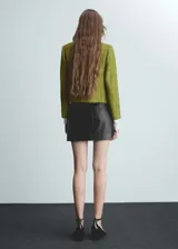 Chaqueta de tweed en color verde lima, con diseño recto, cuello redondo y manga larga. Presenta botones efecto joya y cuatro bolsillos frontales.