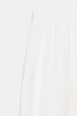 Pantalón blanco de tiro alto con cintura ajustable mediante cordón y puños elásticos en los tobillos. Presenta bolsillos laterales ocultos en la costura.