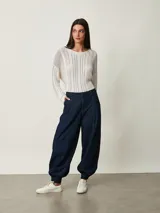 Pantalón slouchy de denim azul oscuro con pinzas en la cintura, bolsillos laterales y puños fruncidos con elástico en los tobillos.