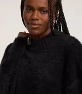 Suéter de punto color crema con cuello redondo y mangas largas ajustadas. Modelo slim alargado con efecto de pelitos.