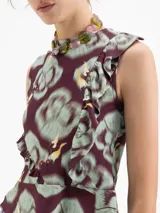 Top sin mangas de viscosa, con escote redondo y volado en el ruedo. Presenta un estampado full print con motivos florales y figuras humanas estilizadas en tonos borgoña, verde menta y amarillo.