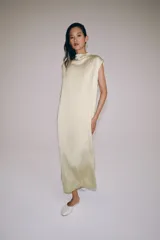 Vestido midi de Zara Woman Collection confeccionado en hilatura de viscosa con tejido satinado, de color beige. Presenta cuello subido, diseño sin mangas (manga sisa), bajo recto con aberturas laterales y cierre en la espalda con alamares.