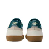Championes New Balance Numeric 272, modelo de skate con diseño en tonos beige y detalles en verde azulado. Presenta una suela de goma color caramelo, cuerpo de lona y gamuza, y el logo característico en el lateral.