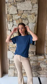 Blusa de manga corta color azul oscuro con textura arrugada o plisada, cuello redondo con borde festoneado.