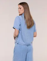 Camisa de corte recto y calce fluido color celeste, confeccionada en lyocell con efecto lavado, cuello camisero tradicional, botones a tono, dos bolsillos aplicados en el pecho y mangas cortas.