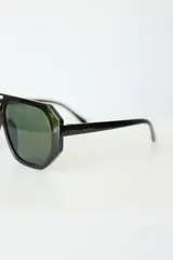 Lentes de sol con armazón de policarbonato negro y cristales tonalidad ámbar, con diseño de puente doble estilo aviador.
