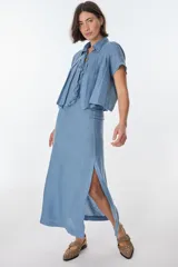 Falda larga de lino color azul claro, de corte recto con tajo lateral. Se combina con un top corto de lino del mismo color con cuello y detalle de lazos frontales.