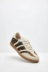 Zapatilla urbana con estampado animal print de leopardo en los laterales y puntera, combinada con cuero beige y detalles blancos. Suela de goma color caramelo y tostado.