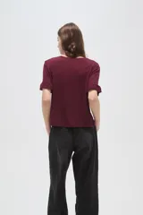 Remera negra de viscosa con textura acanalada, cuello redondo y mangas cortas terminadas en volados.
