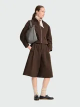 Bolso de mano tipo tote de la línea Le Pliage One de Longchamp, en color bordó. Presenta un diseño minimalista con cierre de cremallera superior, solapa con botón a presión y asas cortas de cuero.