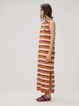 Vestido midi sin mangas de corte holgado, con diseño de rayas horizontales en tonos verde azulado, marrón y rosado. Presenta cuello redondo y aberturas laterales en el dobladillo.