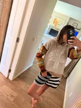 Sweater canguro de lana color beige con capucha, bordado a mano con un árbol en el frente y mangas a rayas en tonos tierra.