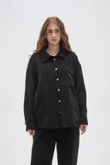 Camisa de pana negra con cuello clásico, cierre frontal de botones y bolsillo en el pecho.