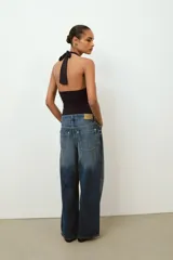 Body de cuello halter con espalda descubierta, confeccionado en poliamida. Presenta un diseño drapeado en los laterales y una abertura frontal con detalle metálico. Posee cierre con botones a presión en la parte inferior y lazada en el cuello.