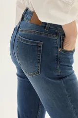 Jean de mezclilla azul de tiro medio, con silueta ligeramente acampanada desde la rodilla.