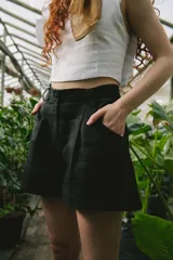 Short negro de tiro alto, con pinzas frontales y calce amplio. Presenta cierre y botón forrado en el frente.