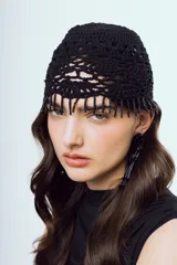 Gorro negro tejido a crochet de diseño artesanal con trama calada y flecos de mostacillas colgantes en el borde frontal.