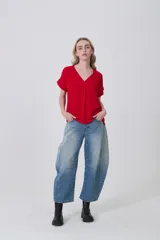 Blusa de poliéster color blanco con cuello en V, mangas cortas con dobladillo y corte holgado.