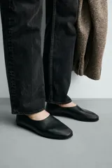 Mocasín de piel color negro con construcción desestructurada que permite usarlo como zapato destalonado. Cuenta con horma redonda, forro y plantilla de piel, y suela de goma VIBRAM®.