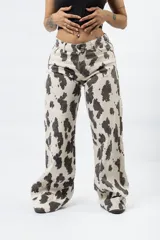 Pantalón wide leg con estampado de vaca en blanco y negro, de tiro alto y cierre de botón y cremallera.