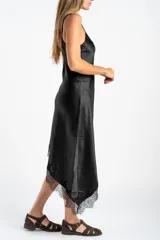 Vestido midi de satén negro con escote en V y tirantes finos. Presenta un diseño asimétrico en el ruedo con detalle de encaje aplicado.