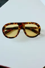 Lentes de sol con armazón de policarbonato con estampado carey y cristales amarillos. Diseño de estilo aviador con puente superior recto.