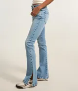 Pantalón bootcut de tiro alto en denim azul claro, ceñido en caderas y muslos con corte acampanado hacia el bajo y detalle de pequeña abertura lateral en los tobillos. Cuenta con bolsillos y cierre tradicional con botón y cremallera.