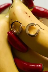 Aros tipo argolla de diseño plano y minimalista, fabricados en acero quirúrgico hipoalergénico con acabado dorado.