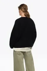 Sweater de punto en color blanco, confeccionado en una mezcla de lana y mohair. Posee un diseño de corte recto con escote en pico, mangas largas de sisa caída y acabados acanalados.