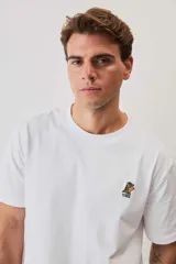 Remera blanca de manga corta y corte holgado, con cuello redondo y pequeño estampado en el pecho.