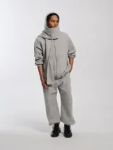 Buzo hoodie oversize de felpa de algodón color gris, con capucha y bufanda integrada que envuelve el cuello. Presenta cierre frontal y bolsillos canguro.