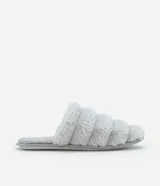 Pantufla abierta de diseño acolchado con gajos, confeccionada completamente en tejido peludo de poliéster de color gris claro, con suela plana.