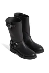 Borcego de cuero color marrón con apliques plateados, caña alta y suela track.