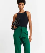 Pantalón de crepé rojo, modelo estilo pijama, de corte fluido, con cintura elástica y lazo de ajuste con terminales metálicas. Cuenta con bolsillos laterales y cierre frontal con cremallera y botón.