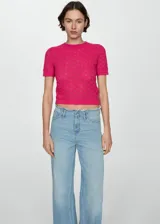 Buzo de tejido calado color fucsia, con cuello redondo y manga corta. Presenta un diseño de punto con textura geométrica y terminaciones acanaladas.