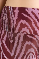Pantalón de corte amplio con diseño de capas y cintura elástica con lazo frontal ajustable. Presenta un estampado animal print en tonos bordó y rosado.