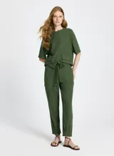Pantalón jogger verde de tejido de punto con corte recto, cintura con trabillas y cordón ajustable con puntas de madera. Presenta bolsillos laterales con solapa y pespuntes.