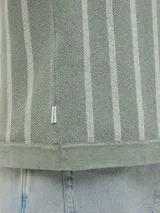 Polo de punto verde con rayas verticales blancas, corte relajado, cuello tipo camisa, cierre con botones y mangas cortas.