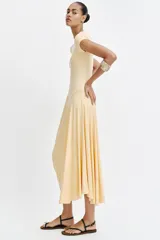 Vestido largo color amarillo pastel, confeccionado con mezcla de viscosa, con cuello redondo, manga corta y bajo asimétrico fruncido con volumen.