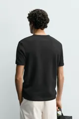 Camiseta de manga corta con cuello panadero y cierre frontal de tres botones. Presenta una textura acanalada y un corte regular fit.