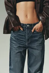 Jeans de mujer, tiro alto, color azul medio con efecto desgastado (lavado claro en muslos y oscuro en bordes). Corte recto y ancho (mom fit) con cinco bolsillos y cierre frontal de botón y cremallera.